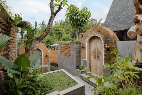 a garden with a wooden door and a fence at Agastya Ubud Villa in Ubud