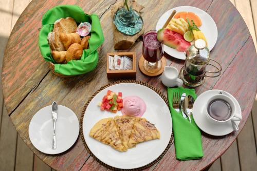 a wooden table with plates of food on it at Agastya Ubud Villa in Ubud