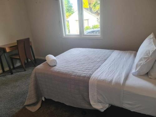 a bedroom with a bed with a window and a table at KK Boarding Holiday house in Hamilton