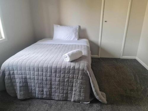 a bed with a white pillow sitting on top of it at KK Boarding Holiday house in Hamilton