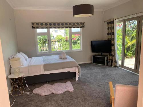 a bedroom with a bed and a flat screen tv at KK Boarding Holiday house in Hamilton