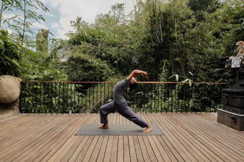 a man doing a yoga pose on a yoga mat at Agastya Ubud Villa in Ubud