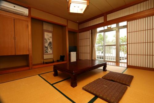 a living room with a table and a large window at 城下町に佇む癒しの宿 旅館 大政 in Karatsu