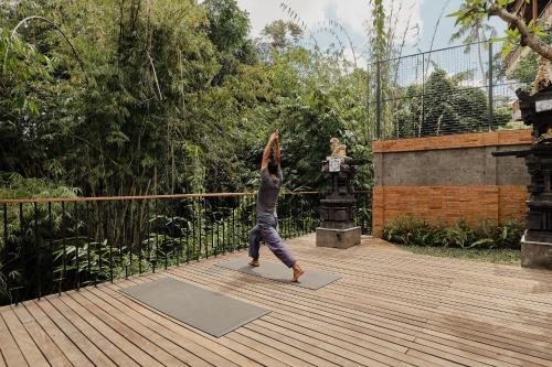 a person doing a yoga pose on a yoga mat at Agastya Ubud Villa in Ubud
