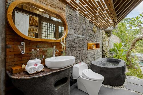 a bathroom with a toilet and a sink and a tub at Agastya Ubud Villa in Ubud