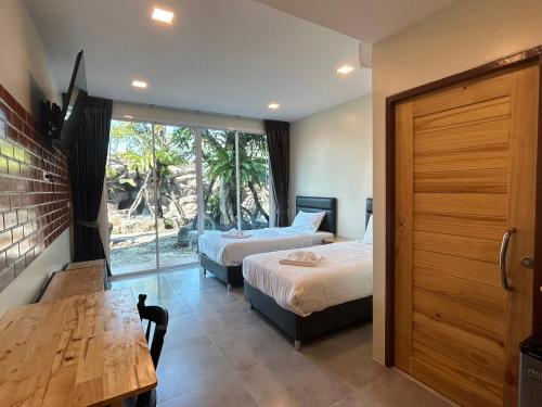 a bedroom with two beds and a table and a window at Uthaithani Resort in Uthai Thani