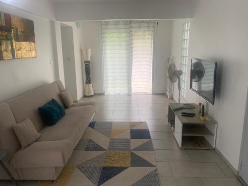 a living room with a couch and a table at F3 dans maison individuelle avec jardin arboré in Le Lamentin