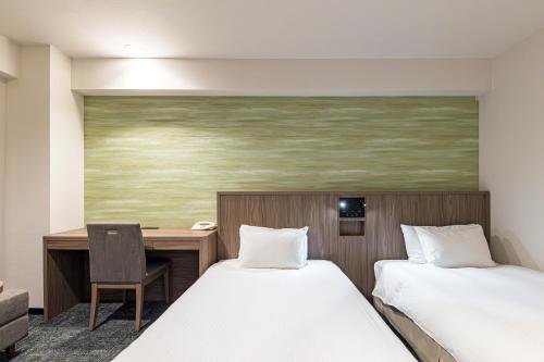 a hotel room with two beds and a desk at Hotel JAL City Nagano in Nagano