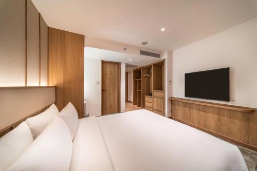 a bedroom with a white bed with a flat screen tv at Sotetsu Grand Fresa Bangkok in Bangkok