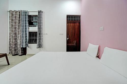 a bedroom with a large white bed and a wooden door at OYO Parth Logistics in Rewāri