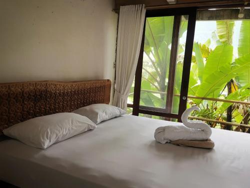 a bed with a towel on it with a window at Alpha 3 Eco Cabin in Rantepao