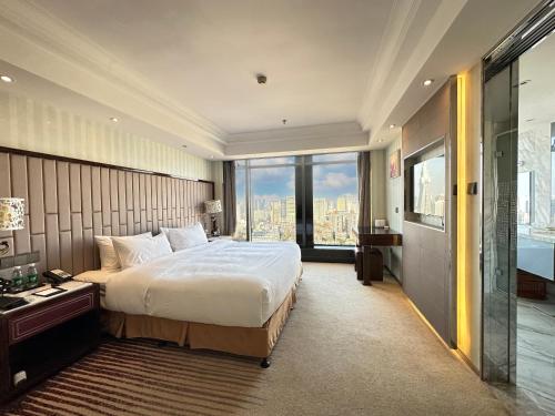 1 dormitorio con cama grande y ventana grande en Suning Universal Hotel ALL-SUITES en Nankín
