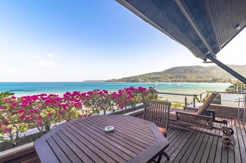 a wooden deck with a table and a view of the ocean at Kamala Beach Estate Resort - SHA Extra Plus in Kamala Beach