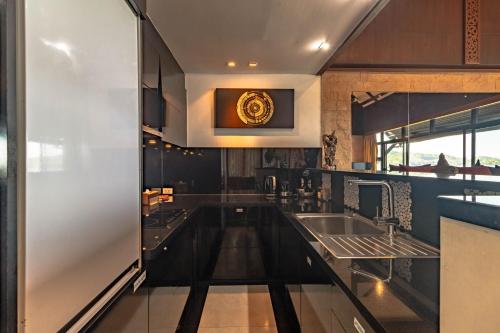 a kitchen with black cabinets and a sink at Kamala Beach Estate Resort - SHA Extra Plus in Kamala Beach