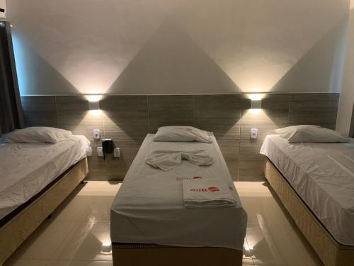 a room with two beds and lights on the wall at Hotel Mundial in Patos