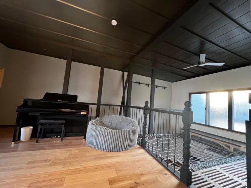 a living room with a piano and a chair at 貸し切りゲストハウスsai2nd in Yasugi