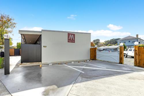 a parking lot with a white building with a garage at Matakana Motel in Matakana