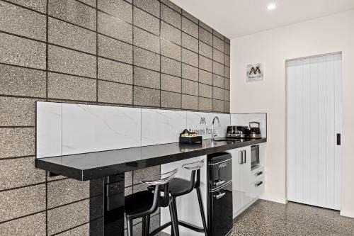 a kitchen with a counter and two stools in it at Matakana Motel in Matakana