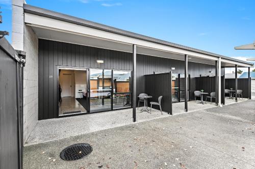 a building with large windows with tables and chairs at Matakana Motel in Matakana