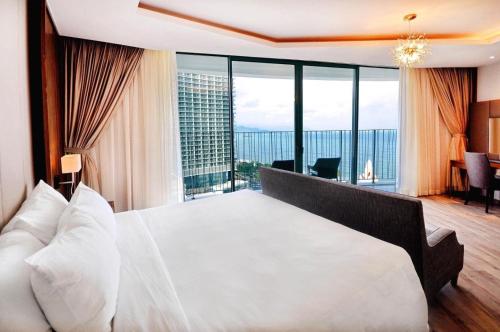 a bedroom with a large white bed with a large window at Panorama Nha Trang Condotel by One in Nha Trang