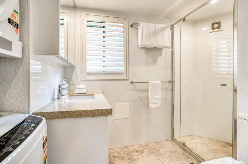 uma casa de banho branca com um chuveiro e um lavatório. em Ocean Breeze Resort em Noosa Heads