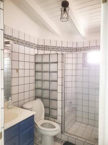 a white tiled bathroom with a toilet and a shower at Ocean view house - Plaza del Mar in Rosarito