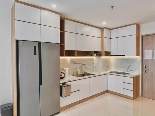 a kitchen with white cabinets and a refrigerator at Homestay Sài Gòn-Vinhomes Grand Park Quận 9-Plus 2PN in Long Bình
