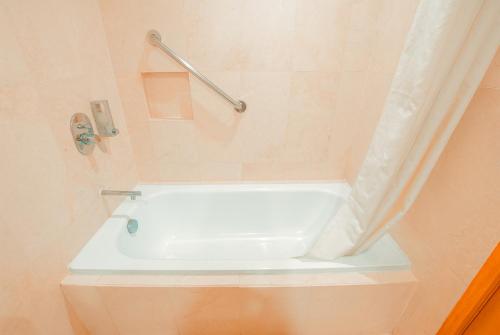 a white bath tub in a bathroom with a shower curtain at City Garden Suites Manila in Manila