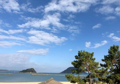 a view of a beach with trees and the ocean at 城下町に佇む癒しの宿 旅館 大政 in Karatsu