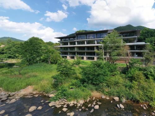 a building on a hill next to a river at Chalet Ivy Jozankei in Jozankei