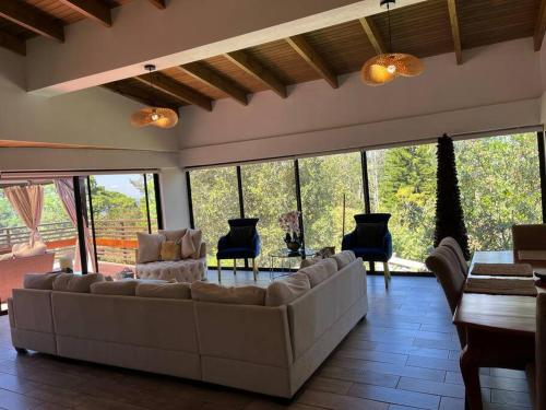 a living room with a couch and chairs and windows at Casa de ensueño, jacuzzi-fogata in La Cuadrilla