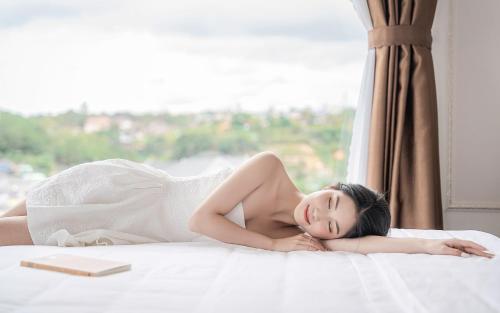 a woman in a white dress laying on a bed at PINE VIEW Hotel Dalat in Da Lat