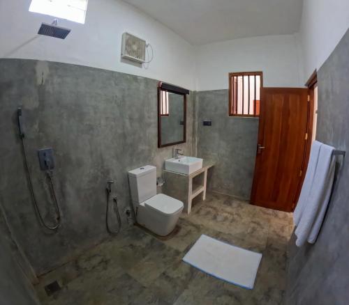 a bathroom with a toilet and a sink and a shower at SurfBayVilla in Dickwella