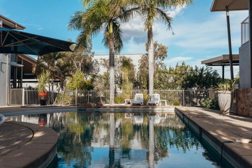 a swimming pool with two chairs and palm trees at The Mayfair Ridge Hotel in Emerald