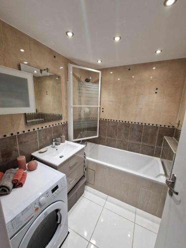La salle de bains est pourvue d'une baignoire, d'un lavabo et d'un lave-linge. dans l'établissement Appartement comfortable à 200 m à pied du RER A, à Champs-sur-Marne