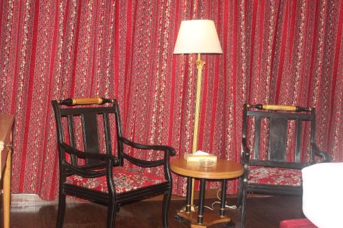 a room with two chairs and a table with a lamp at Mehran Hotel Karachi in Karachi