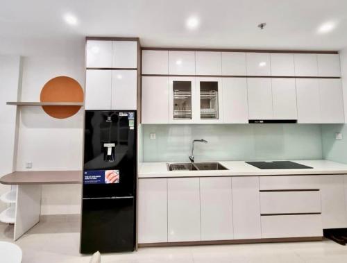 a kitchen with white cabinets and a black refrigerator at Luxury Apartment-Bống Homestay in Long Bình