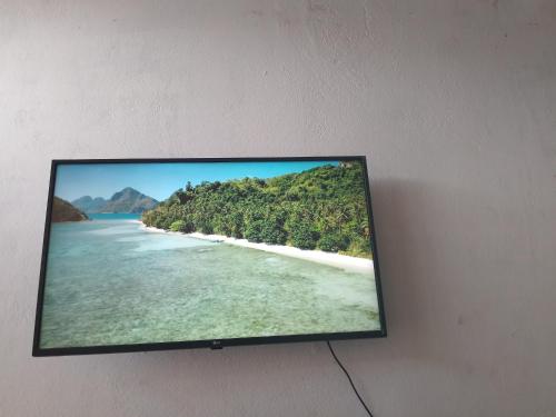 a flat screen tv hanging on a wall with a beach at casa tranquila in Naranjo