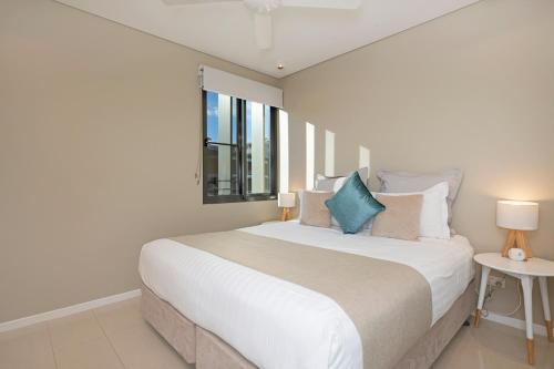 a white bedroom with a large bed and a window at Darwin Waterfront Luxury Suites in Darwin