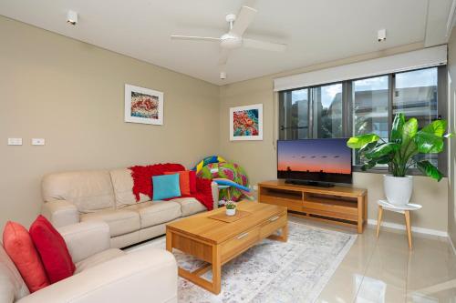 a living room with a couch and a flat screen tv at Darwin Waterfront Luxury Suites in Darwin