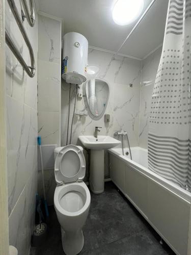 a white bathroom with a toilet and a sink at 1-комн квартира в центре города in Qyzylorda