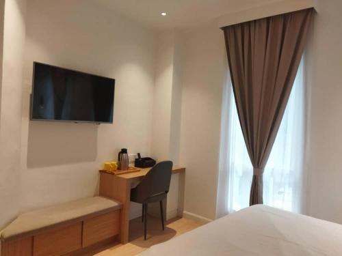 um quarto de hotel com uma secretária e uma televisão na parede em AP Concept Hotel em Petaling Jaya
