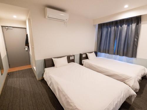 um quarto de hotel com duas camas e uma janela em Hotel Taiyo Noen Tokushima Kenchomae em Tokushima