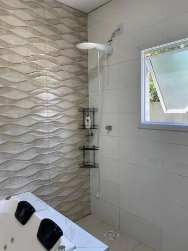 a bathroom with a shower with a sink and a window at Casa com banheira e lareira 12km da cidade in Santa Cruz do Sul