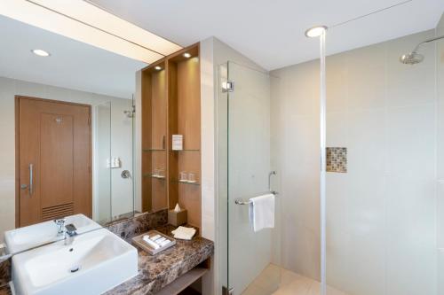 y baño con lavabo y ducha. en Swiss-Belhotel Danum Palangkaraya en Palangkaraya