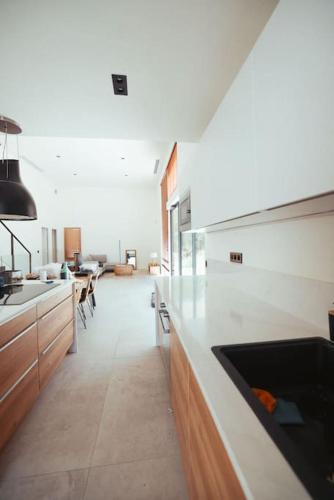 une cuisine avec des comptoirs blancs et un salon dans l'établissement Villa Contemporaine Architecte, à Bouc-Bel-Air