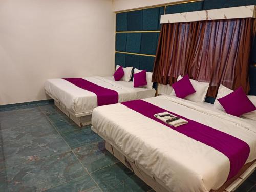 アーメダバードにあるHotel Karnavatiの紫と白のシーツが備わる客室のベッド2台