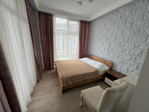 a small bedroom with a bed and a brick wall at Уютный коттедж "PARIS", 30м от пляжа! 3 спальни, терраса и летняя кухня! in Chok-Tal