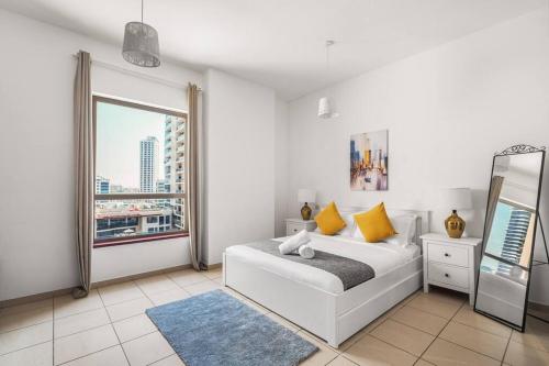 a white bedroom with a bed and a window at Sunkissed holiday homes 2-3BR Apartments on JBR beach near mall & metro & bluewaters Island in Dubai