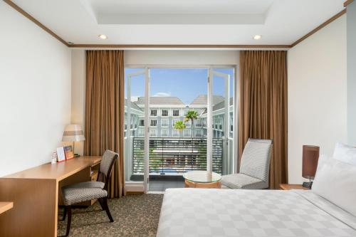 a hotel room with a bed and a desk and a window at Swiss-Belhotel Danum Palangkaraya in Palangkaraya